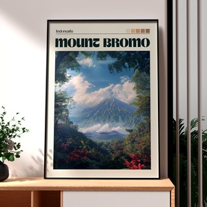 May include: A framed art print depicting Mount Bromo in Indonesia. The image shows a mountain landscape with dense foliage, a cloudy sky, and the text "Mount Bromo". The print is in a black frame.