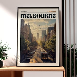May include: A framed art print depicting Melbourne, Australia. The image shows a city street with a tram, buildings, and trees. The word "Melbourne" is in large letters, with "Australia" above.