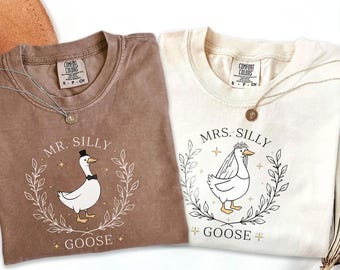 May include: Two brown and cream colored t-shirts with a goose graphic and the text "Mr. Silly Goose" and "Mrs. Silly Goose".