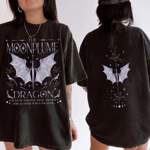 May include: Black t-shirt with a graphic print of a dragon with wings and the text "The Moonplume Dragon" and "For those who feel small and quiet spread those wings and roar".