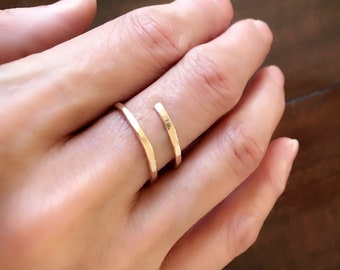 Puede incluir: Un anillo de metal martillado de color dorado con un diseño abierto único. El anillo se lleva en un dedo.