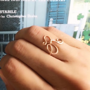 May include: A rose gold wire ring with the letters "S" and "E" intertwined.