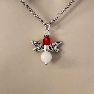 May include: A silver dragonfly pendant necklace with a white bead and a red crystal accent.
