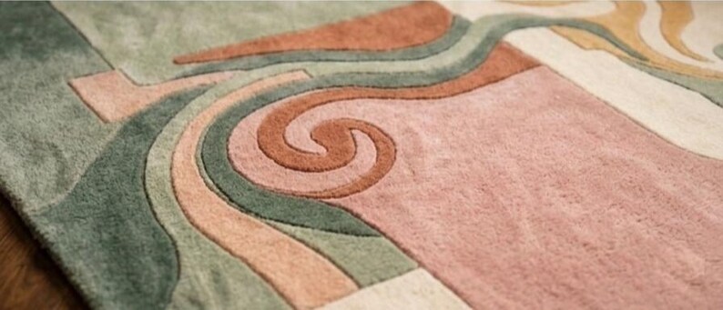 May include: Close-up of a colorful area rug with an abstract design. The rug features a swirl pattern in shades of brown, pink, green, and beige. The rug has a soft, textured appearance, suggesting a comfortable and decorative floor covering.