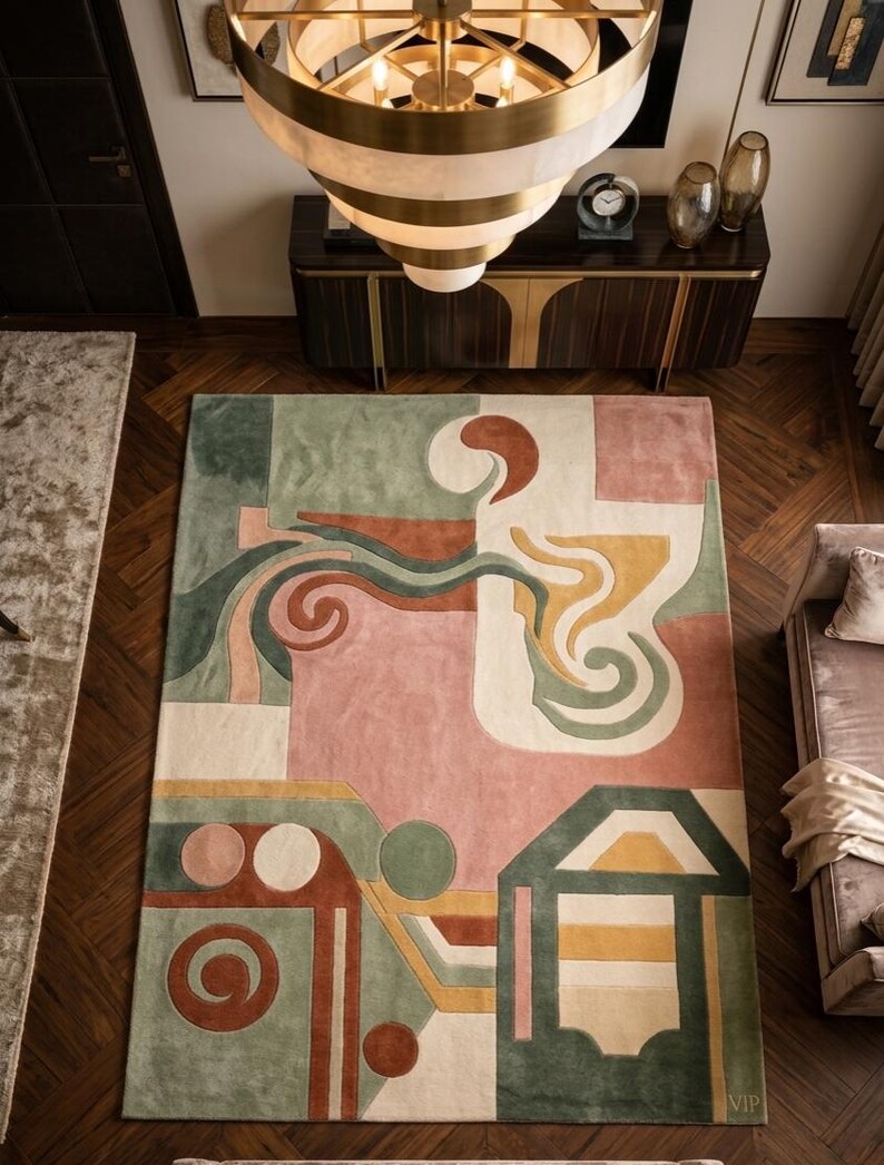 May include: A large rectangular rug with an abstract design in shades of pink, green, orange, and cream. The rug features geometric shapes and flowing lines, creating a modern and artistic aesthetic. The rug is placed on a dark wood floor.