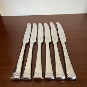 May include: Six silver dinner knives with the words "W. LEIGHTON STAINLESS" engraved on the back of each blade.
