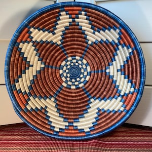 Rwanda sisal geweven kommen. 12 x 12 x 3 inch hemelsblauw, roest- en crèmekleurig ontwerp. Handgeweven spoel vakkundig omwikkeld met sisal.
