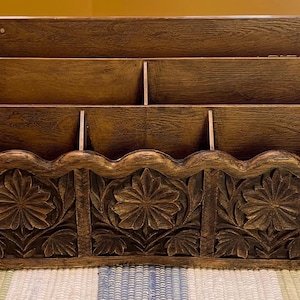 Peut inclure: Un organisateur de courrier mural en bois brun foncé doté de trois compartiments de rangement distincts. Le panneau avant est orné de trois motifs floraux sculptés, chacun présentant des pétales et des feuilles détaillés, avec un bord festonné.