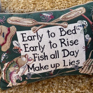 May include: Green rectangular tapestry pillow with the text "Early to Bed Early to Rise Fish all Day Make up Lies". The pillow features fishing-themed imagery, including a fish, oars, and a fishing hat.