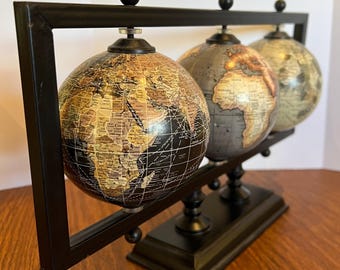 Tres globos terráqueos Repogle World Traveler, pieza central sobre una base de hierro negro. Estos tres globos giratorios de 10 cm (4 pulgadas) de colores intensos tienen un acabado mate.