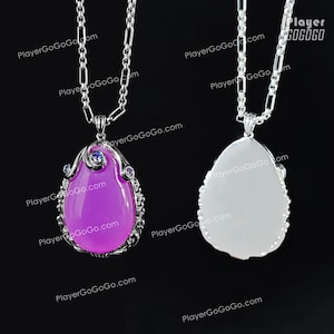 May include: Two silver necklaces with teardrop-shaped pendants. One pendant is a vibrant purple, the other is white. Both are framed with ornate silver and accented with small blue gems. The chain is a delicate silver link.