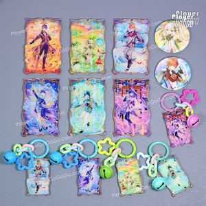 Puede incluir: Una colecci&oacute;n de coloridos colgantes de acr&iacute;lico, llaveros y botones con ilustraciones de personajes de estilo anime. Los llaveros incluyen colgantes en forma de estrella y c&iacute;rculo, campanas y eslabones de conexi&oacute;n. La obra de arte muestra varios personajes en colores vibrantes.