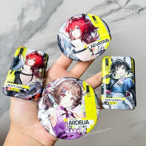 May include: A collection of four anime-style character badges. The badges feature colorful illustrations of female characters with text labels. The badges are in various shapes, including round and rectangular, with yellow and black borders.