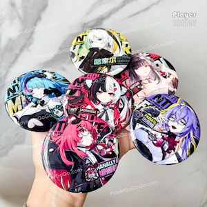 Puede incluir: Una colección de botones redondos de estilo anime. Cada botón presenta un diseño de personaje diferente con colores vibrantes, texto y elementos gráficos. Los botones se sostienen en una mano.