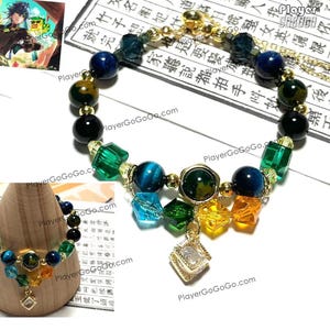 May include: A gold bracelet with blue, green, and brown beads. The bracelet has a gold charm with a clear stone in the center. The bracelet is on a wooden surface.