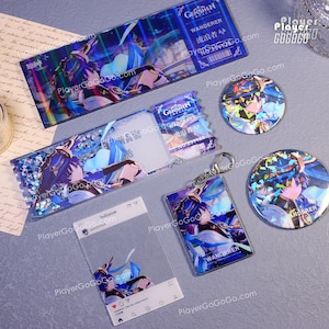Op de afbeelding: Een set Genshin Impact merchandise met het personage Wanderer. De set bevat een holografische kaart, een glitter sleutelhanger, een sticker en twee ronde knoppen. De knoppen en de sleutelhanger zijn in blauw en zwart en tonen het beeld van het personage.