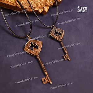 Puede incluir: Dos collares de llave de oro con cordones negros. Cada llave presenta una silueta de un pájaro con plumas. Las llaves están sobre un fondo oscuro con el texto "PlayerGoGoGo.com" repetido varias veces.