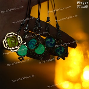 May include: Five keychains with different designs. The keychains are made of metal and have a gold finish. The designs include a square with a green and yellow symbol, a circle with a blue and white symbol, and three circles with green and blue symbols. The keychains are hanging from a hand.