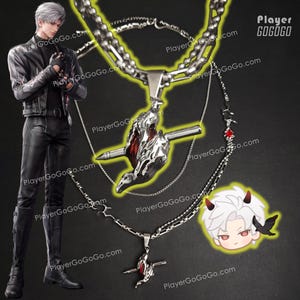 May include: Three silver necklaces with different pendant designs. The top necklace features a large pendant of a bird with a red gem and a silver spike. The middle necklace has a smaller pendant of a bird with a red gem and a silver spike. The bottom necklace has a pendant of a cross with a red gem and a silver spike. The necklaces are on a black background. PlayerGoGo.com is printed on the background.