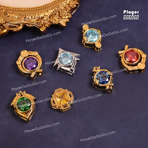 May include: Six gold-tone pendants with colourful gemstones. Each pendant features a different design and gemstone, including purple, blue, green, red, and yellow.