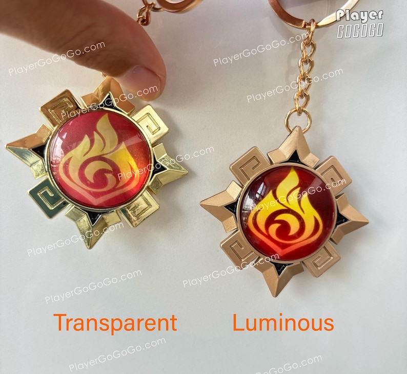 Pu&ograve; includere: Due portachiavi dorati con un designo a fiamma rosso e giallo. Il portachiavi a sinistra ha uno sfondo trasparente, mentre il portachiavi a destra ha uno sfondo luminoso. Il testo "Player GOGOGO" &egrave; visibile nell'angolo in alto a destra dell'immagine.