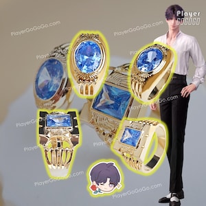 May include: Four gold rings with blue gemstones. The rings are set with different shaped stones, including oval, square, and rectangular. The rings are displayed on a white background.
