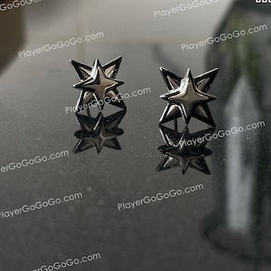 以下が含まれることがあります： 黒い背景に銀色の星型のイヤリングのペア