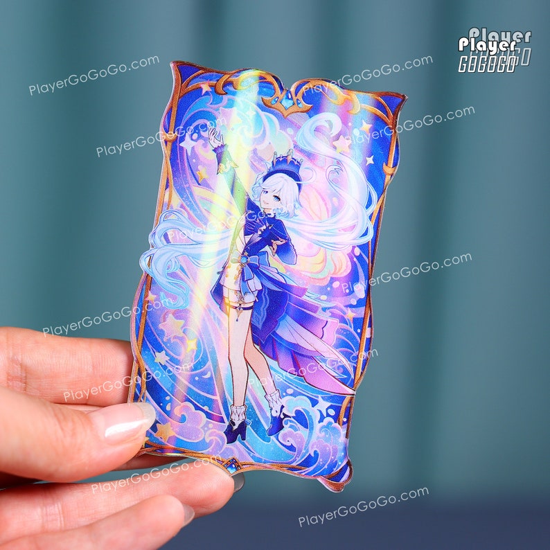 Puede incluir: Un charm rectangular de acr&iacute;lico con una ilustraci&oacute;n de estilo anime. La obra de arte representa un personaje en azul y blanco, rodeado de estrellas y olas. El charm tiene un borde dorado y est&aacute; sostenido por una mano.