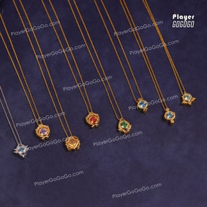 May include: Nine gold necklaces with different coloured gemstone pendants. The pendants are in the shapes of a flower, a teardrop, and a star. The necklaces are on a blue background. PlayerGoGoGo.com is printed on the background.