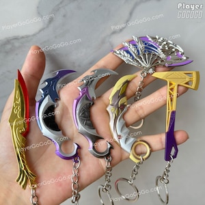 K&ouml;nnte beinhalten: F&uuml;nf verschiedene Schl&uuml;sselanh&auml;nger mit Charakteren aus dem Videospiel Valorant. Die Schl&uuml;sselanh&auml;nger sind aus Metall und Kunststoff und in verschiedenen Farben gehalten, darunter Gold, Lila, Silber und Schwarz. Die Schl&uuml;sselanh&auml;nger sind alle an silbernen Ketten befestigt.