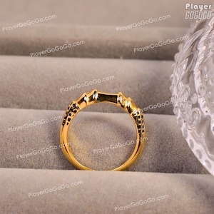 May include: A gold ring with a textured design. The ring is on a gold-colored surface.