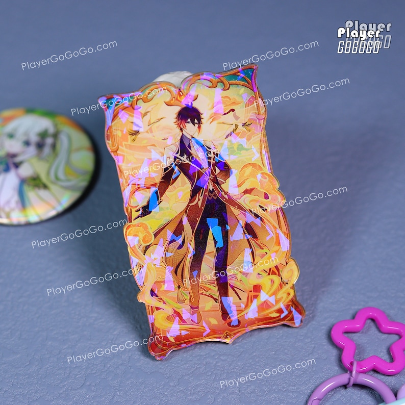 Puede incluir: Un charm acr&iacute;lico hologr&aacute;fico rectangular con una ilustraci&oacute;n de personaje. El charm tiene una combinaci&oacute;n de colores dorados y naranjas con una imagen detallada de una persona con un abrigo largo. El charm est&aacute; rodeado por un borde decorativo.