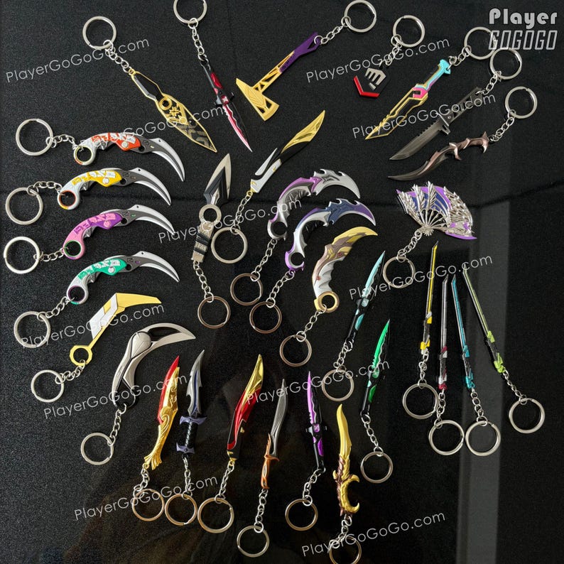 K&ouml;nnte beinhalten: Eine Sammlung von 20 bunten Schl&uuml;sselanh&auml;ngern aus Metall mit verschiedenen Waffendesigns, darunter Messer, Schwerter und &Auml;xte. Die Schl&uuml;sselanh&auml;nger sind auf einem schwarzen Hintergrund angeordnet, auf dem der Text "PlayerGoGoGo.com" zu sehen ist.