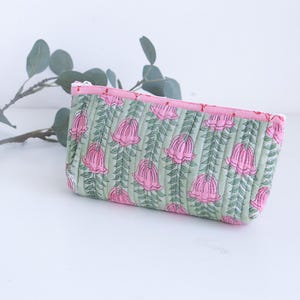 May include: A quilted cosmetic bag with a floral pattern. The bag features a light green background with pink flowers and green stems. The zipper and interior lining are pink.