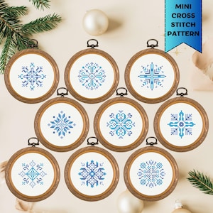 Op de afbeelding: Negen mini kruissteekpatronen in houten ringen, elk met een uniek blauw en turquoise sneeuwvlokontwerp. De ringen zijn in een cirkelvorm gerangschikt, met een banner met de tekst "MINI CROSS STITCH PATTERN".