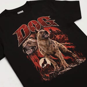 Peut inclure: Un t-shirt noir à manches courtes avec une impression graphique représentant un chien brun tacheté aux dents découvertes. Le mot DOG est imprimé en grandes lettres rouges usées au-dessus. Le motif inclut la silhouette d'un chien.