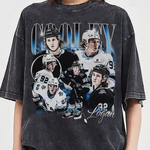 May include: Dark gray t-shirt featuring a collage of hockey player images with the name "COOLEY" in large, stylized text. The design includes images of the player in various poses, wearing a helmet and jersey with the number 92.