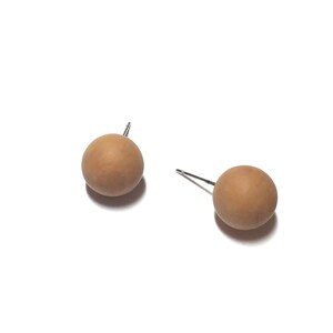 May include: A pair of brown wooden ball stud earrings. The earrings are simple and minimalist.