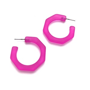 May include: A pair of pink octagon-shaped hoop earrings. The earrings are made of a frosted plastic material.