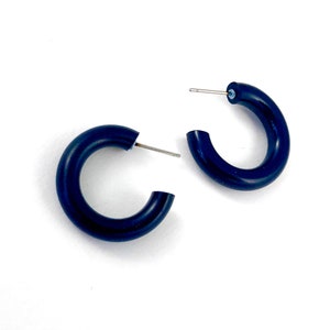 May include: A pair of black hoop earrings. The earrings are made of a thick, round, black material.