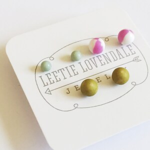 May include: A set of six small, round earrings in various colors. The earrings are displayed on a white card with the text "Leetie Lovendale Jewelry".