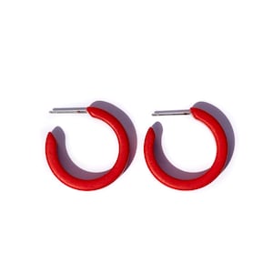 May include: A pair of red hoop earrings with a silver post. The earrings are simple and elegant.
