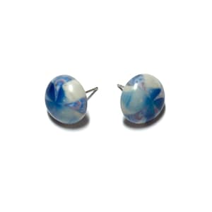 May include: A pair of stud earrings with a marbled design. The earrings are round and feature a mix of white, light blue, and dark blue colors. The studs have silver posts.