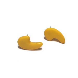 May include: A pair of yellow abstract shaped earrings. The earrings are made of a smooth, glossy material.