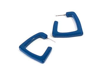 May include: A pair of blue triangle shaped hoop earrings. The earrings are made of a smooth, glossy material.