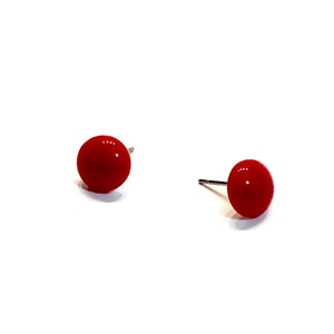 May include: A pair of bright red, round stud earrings. Each earring features a glossy, spherical design with a silver post. The earrings are set against a clean white background, highlighting their vibrant color and simple elegance.