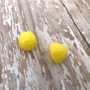 May include: A pair of yellow stud earrings. The earrings are round and have a glossy finish.