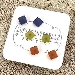 May include: A set of four square-shaped earrings in blue, green, and orange. The earrings are displayed on a white card with the text "Leete Lovepale Jewelry".