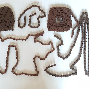 May include: Arrangement of brown metal bicycle chains in various shapes against a white background. The chains are in the shapes of a heart, a spiral, and other abstract forms. The chains are linked together.