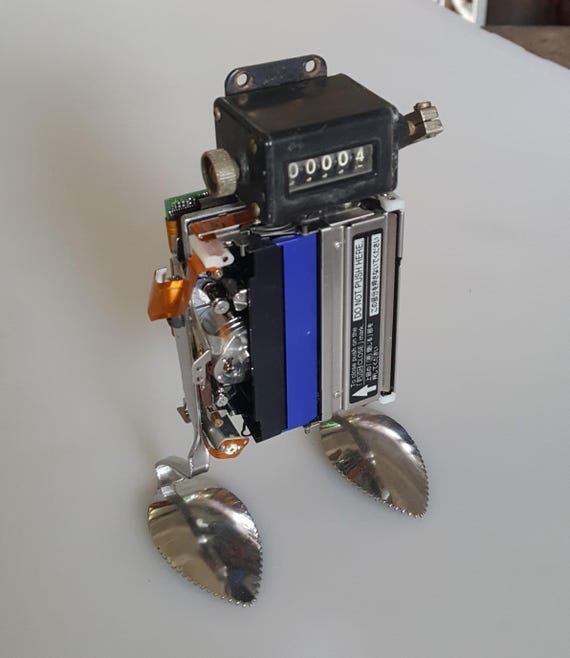 One-of-a-kind robot sculpture assembled from salvaged vintage electronics — every piece is genuinely unique and tells a story about the parts it's made from.